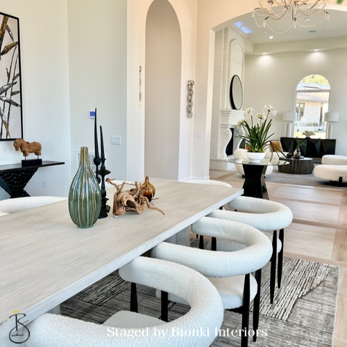 Luxury open-concept dining and living area staging featuring curved seating and refined accessories designed to emphasize architectural flow. Staged by Bionki Interiors.