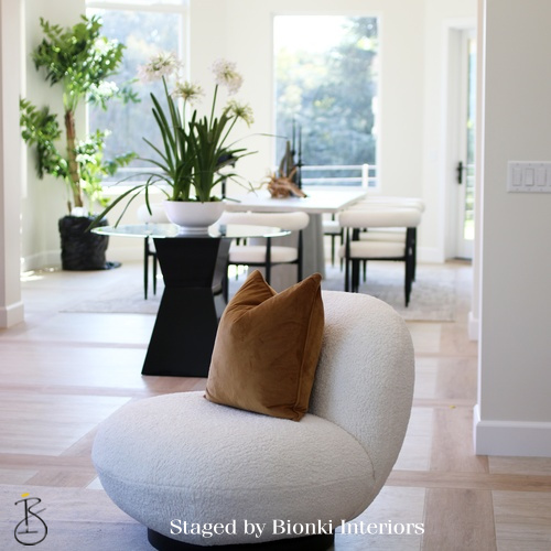 Luxury open-concept staging featuring sculptural seating and organic textures designed to highlight flow between living and dining areas. Staged by Bionki Interiors.