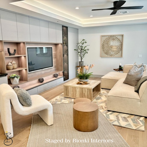Luxury vacant home staging for a modern living room featuring a built-in media wall, warm wood tones, and layered textures. Staged by Bionki Interiors.