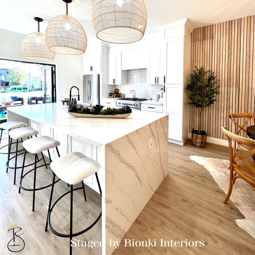 Luxury kitchen staging featuring a waterfall island, modern barstools, and warm wood accents designed to highlight functionality and buyer appeal. Staged by Bionki Interiors.