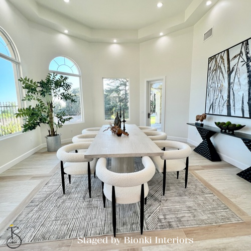 Luxury dining room staging in a light-filled space featuring a long table and sculptural seating designed to showcase entertaining potential. Staged by Bionki Interiors.