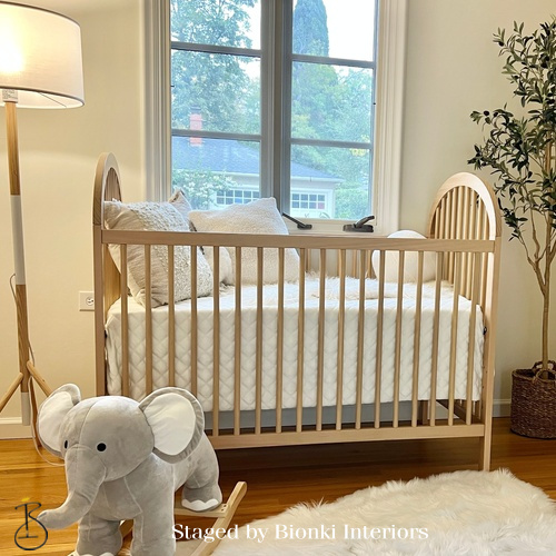 Luxury nursery staging featuring a natural wood crib and soft neutral textiles. Staged by Bionki Interiors.