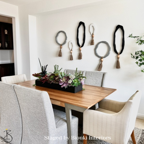Luxury dining room staging featuring a natural wood table, upholstered seating, and curated wall accents designed for everyday living and entertaining. Staged by Bionki Interiors.