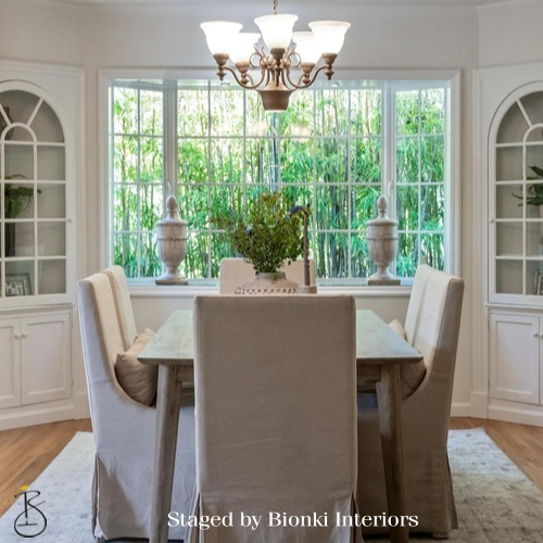Luxury dining room staging featuring upholstered seating and garden-facing windows. Staged by Bionki Interiors.